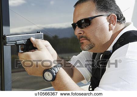 Stock Photo - Security guard aiming with gun outdoors. Fotosearch