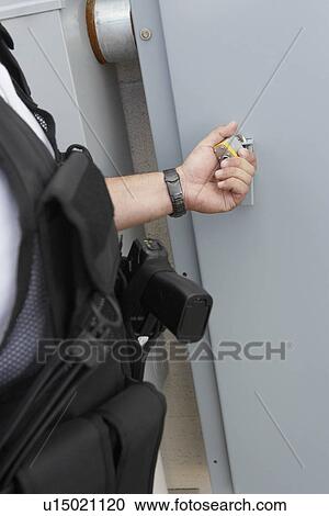 Stock Image - Security guard checking padlock, mid section. Fotosearch