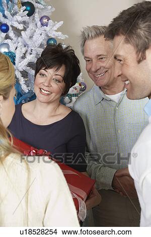 Picture - Senior couple and mid adult couple in front of Christmas tree. Fotosearch