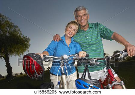 Stock Photography - Senior couple on bicycles at dusk, portrait. Fotosearch