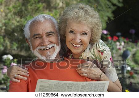 Picture - Senior couple reading newspaper in garden, portrait. Fotosearch