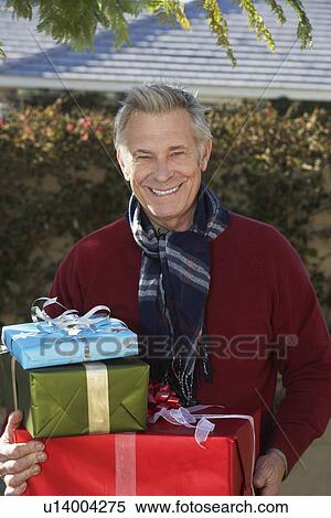 Stock Photography - Senior man holding presents outside. Fotosearch