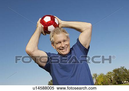 Senior man holding soccer ball over head, outdoors View Large Photo Image Stock Photography - Senior man holding soccer ball over head, outdoors. Fotosearch