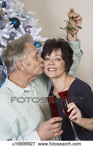 Senior man kissing woman under mistletoe View Large Photo Image Stock Photo - Senior man kissing woman under mistletoe. Fotosearch