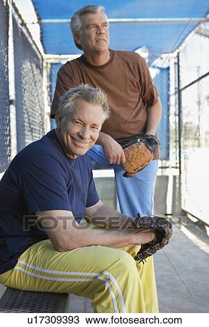 Stock Image - Senior men sitting in baseball dugout. Fotosearch