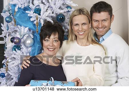 Senior woman and mid adult couple in front of Christmas tree, portrait View Large Photo Image Stock Photo - Senior woman and mid adult couple in front of Christmas tree, portrait. Fotosearch