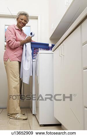 Stock Photo - Senior woman doing laundry at home. Fotosearch