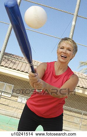 Picture - Senior woman hitting softball. Fotosearch