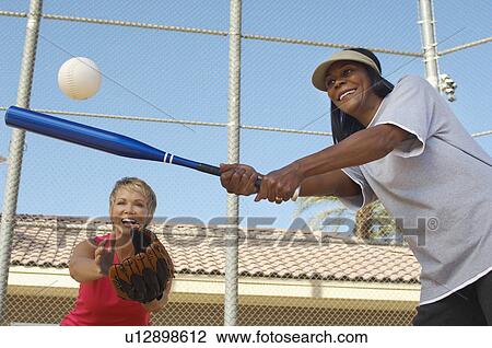 Senior woman hitting softball with other woman catching View Large Photo Image Stock Image - Senior woman hitting softball with other woman catching. Fotosearch