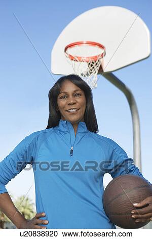 Stock Image - Senior woman on outdoor basketball court, portrait. Fotosearch