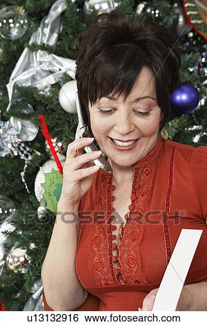 Senior woman using cell phone in front of Christmas tree View Large Photo Image Stock Photograph - Senior woman using cell phone in front of Christmas tree. Fotosearch
