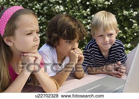 Stock Photo - Shocked Little Kids Looking at a Laptop. Fotosearch