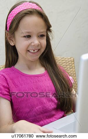 Stock Image - Smiling Little Girl Using a Laptop. Fotosearch