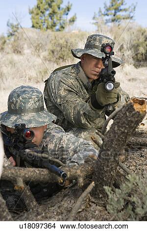 Picture - Soldiers aiming machine gun, leaning on log. Fotosearch