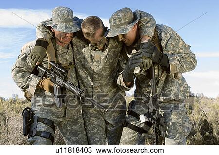 Soldiers walking in field carrying colleague View Large Photo Image Stock Image - Soldiers walking in field carrying colleague. Fotosearch
