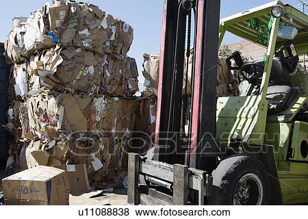 Stock Photo - Stacks of cardboard boxes in recycling centre and forklift truck. Fotosearch