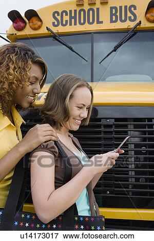 Stock Photo - Students Text Messaging by School Bus. Fotosearch