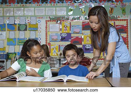 Stock Image - Teacher and pupils in classroom. Fotosearch
