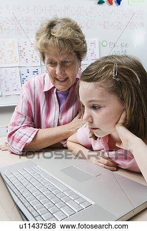 Teacher Helping Schoolgirl Use Laptop View Large Photo Image Stock Photo - Teacher Helping Schoolgirl Use Laptop. Fotosearch