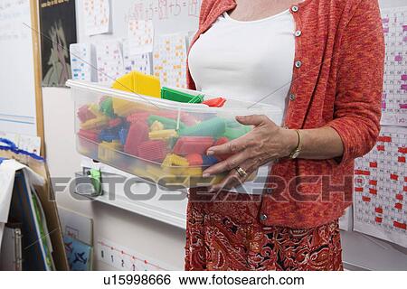 Stock Photograph - Teacher Holding a Box Full of Plastic Puzzle Pieces. Fotosearch