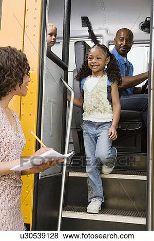 Stock Photo - Teacher Unloading Elementary Students from School Bus. Fotosearch