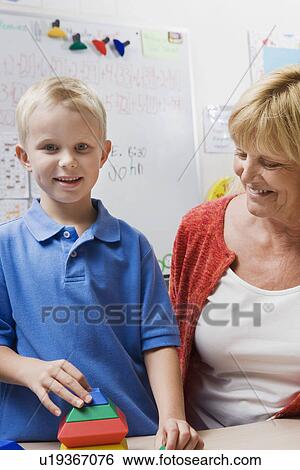 Teacher Watching Little Boy Assemble Educational Puzzle View Large Photo Image Stock Photograph - Teacher Watching Little Boy Assemble Educational Puzzle. Fotosearch