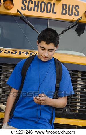 Stock Photograph - Teenager Boy Listening to MP3 Player by School Bus. Fotosearch