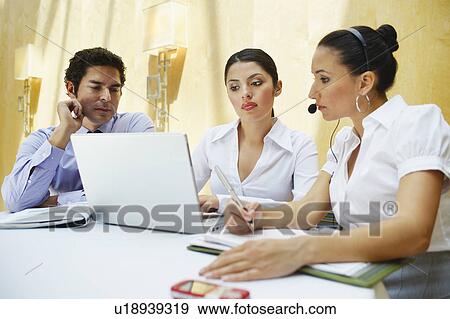Stock Photo - Three business colleagues using laptop in office. Fotosearch
