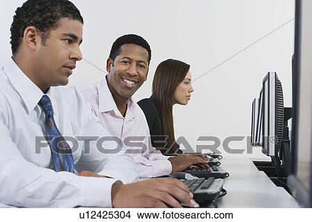 Picture - Three business people using computers in office. Fotosearch