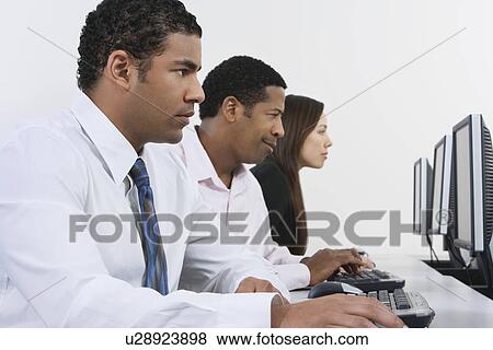 Stock Photo - Three business people using computers in office. Fotosearch