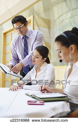 Stock Photo - Three colleagues working in business meeting. Fotosearch