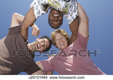 Picture - Three men in huddle, view frombelow. Fotosearch