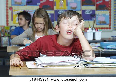 Stock Image - Three pupils in classroom, one of them sleeping. Fotosearch