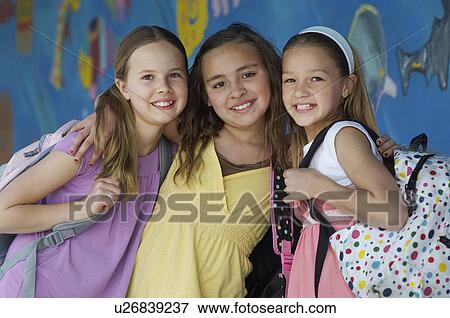 Stock Photo - Three school girls outside school, portrait. Fotosearch