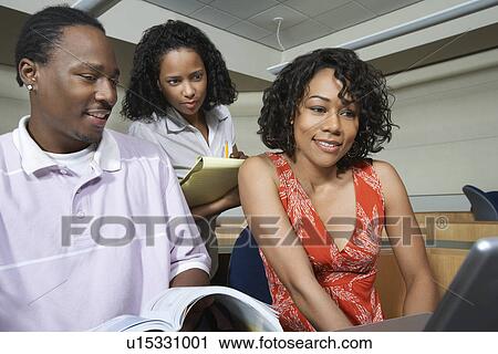 Three students using laptop in lecture theatre View Large Photo Image Stock Image - Three students using laptop in lecture theatre. Fotosearch
