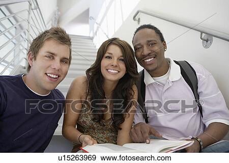 Stock Photo - Three students working on stairs in school, portrait. Fotosearch