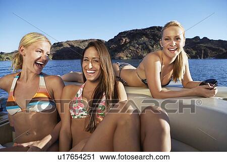 Three young women relaxing in boat on lake View Large Photo Image Stock Image - Three young women relaxing in boat on lake. Fotosearch