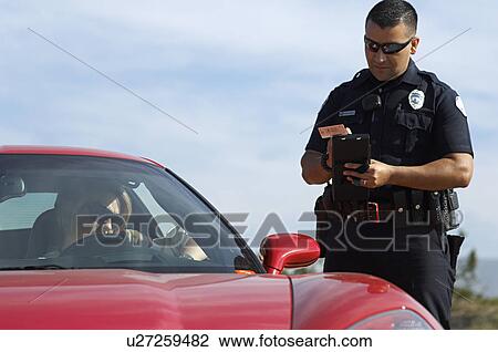Stock Image - Traffic cop standing by sports car. Fotosearch