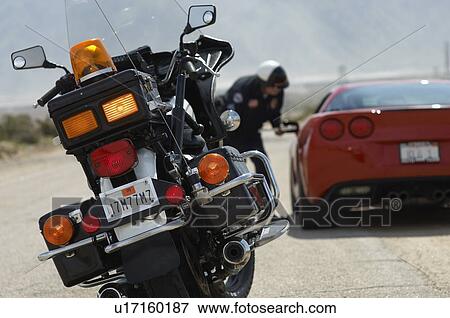Stock Photo - Traffic cop talking with sports car driver, focus on motorcycle in foreground. Fotosearch