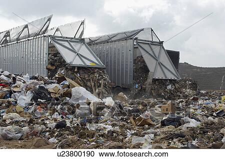Stock Image - Trucks dumping waste at landfill site. Fotosearch