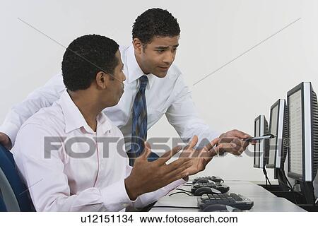 Picture - Two business men discussing in front of computer. Fotosearch