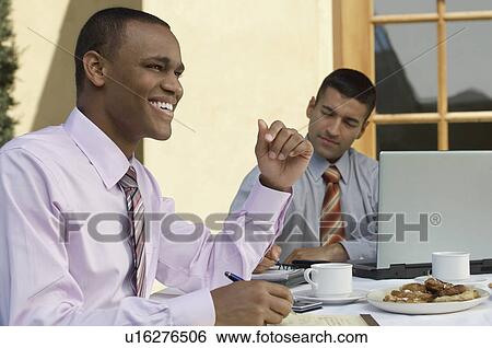 Two business men working at outdoor cafe table View Large Photo Image Stock Photograph - Two business men working at outdoor cafe table. Fotosearch