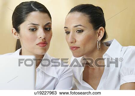 Two business women using laptop in office View Large Photo Image Stock Image - Two business women using laptop in office. Fotosearch