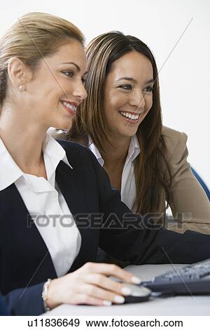 Stock Photo - Two businesswoman smiling over computer. Fotosearch
