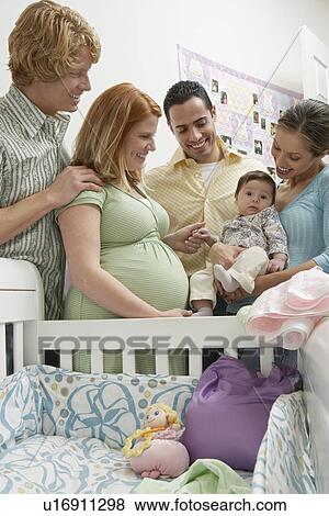Stock Photo - Two couples and baby (1-6 months) by cradle. Fotosearch
