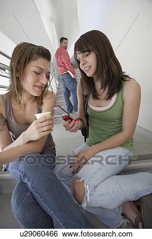 Two female students using mobile phone on stairs View Large Photo Image Stock Photograph - Two female students using mobile phone on stairs. Fotosearch