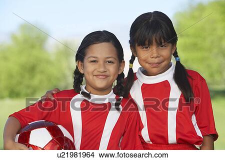 Picture - Two girl soccer players (7-9 years) embracing on soccer field, portrait. Fotosearch