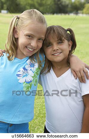 Stock Image - Two girls (7-9 years) hugging, portrait. Fotosearch