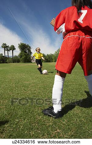 Stock Photograph - Two girls (7-9 years) playing soccer. Fotosearch