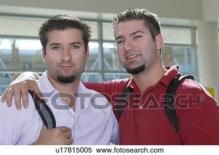 Stock Photography - Two male student embracing, indoors, portrait. Fotosearch